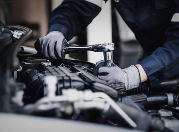 Professional mechanic working on the engine of the car in the garage. Car repair service. The concept of checking the readiness of the car before leaving.